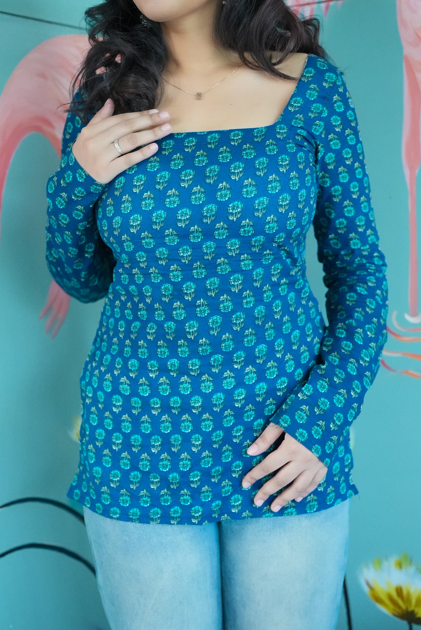 Woman wearing a blue patterned top against a colorful background Karaa