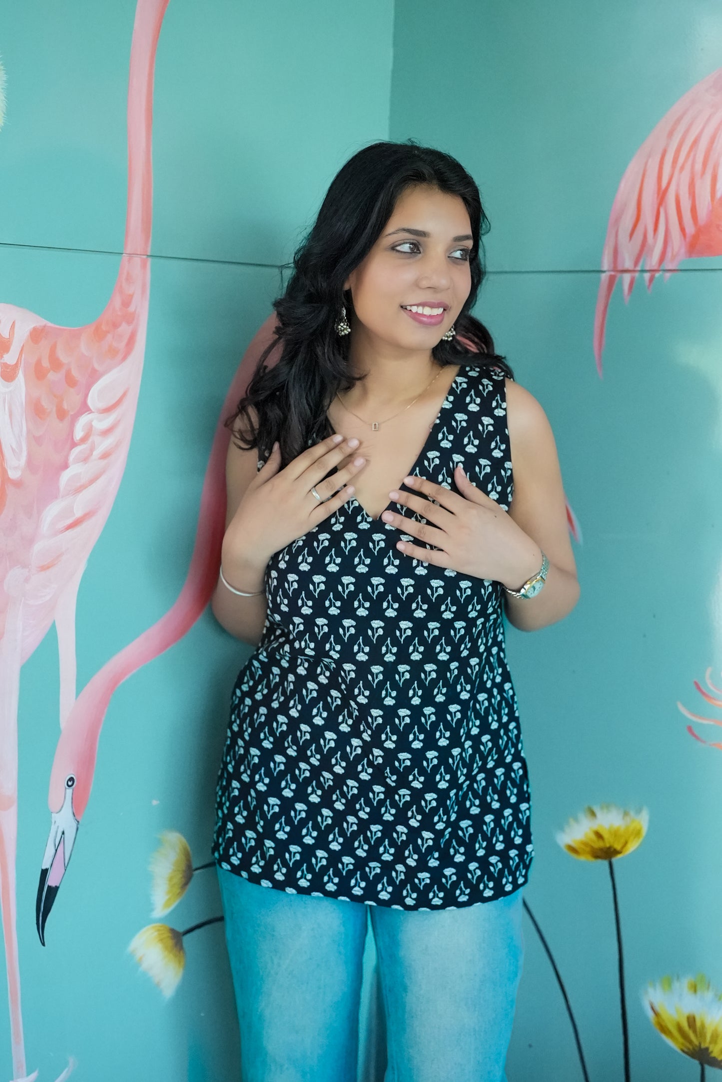 Woman posing in front of a flamingo mural with a teal background  Karaa