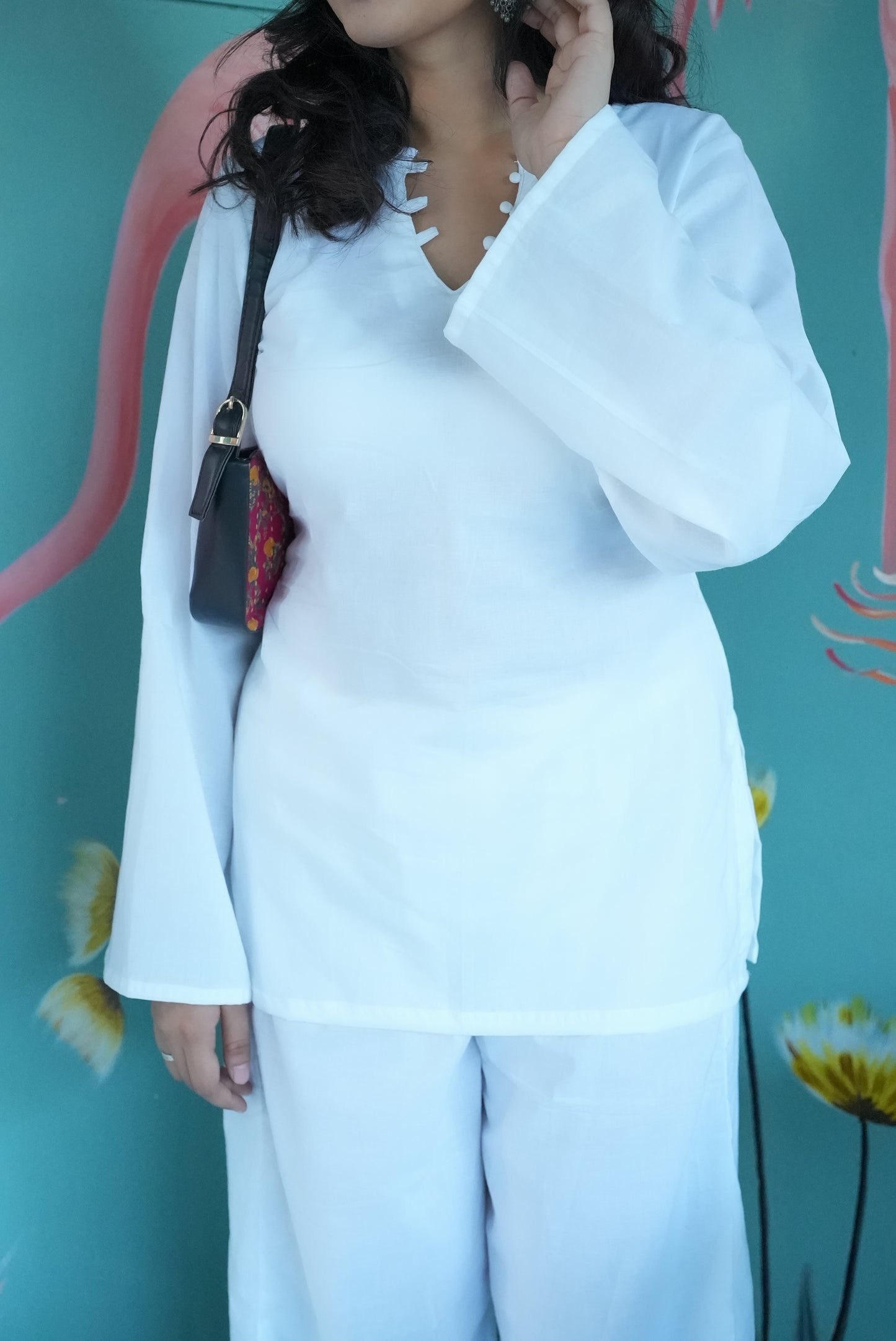 Person wearing a white outfit with a teal background Karaa