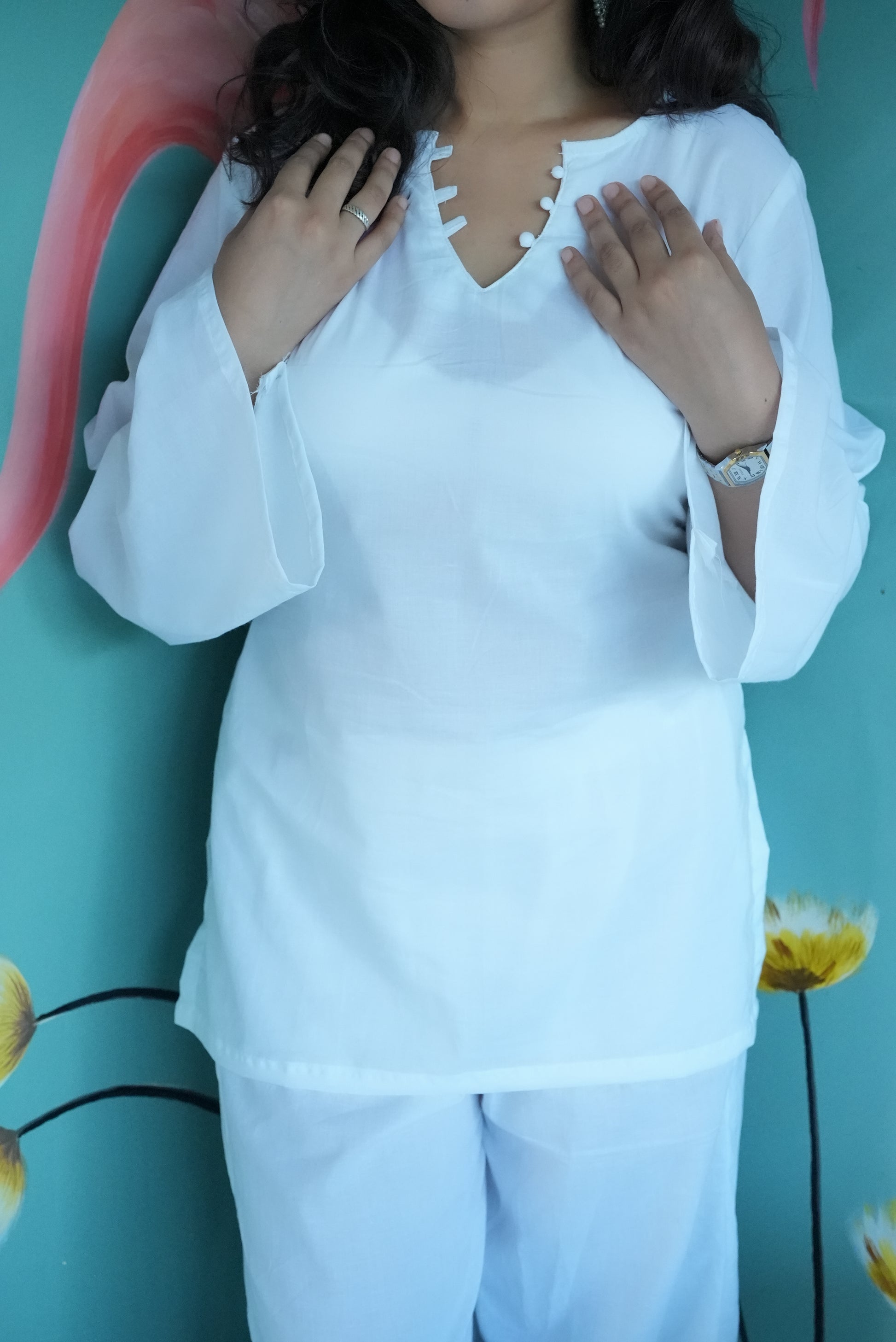 Woman wearing a white outfit with a teal background    Karaa